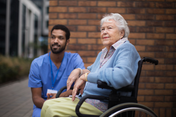 Happy senior woman at a wheelchair spending time outside with her assistant.