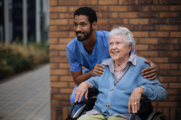 Happy senior woman at a wheelchair spending time outside with her assistant.