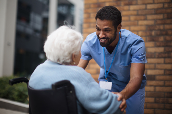 Senior woman at a wheelchair spending time outside with her assistant.