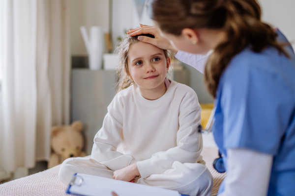 Young doctor taking care of little girl in a hospital room.