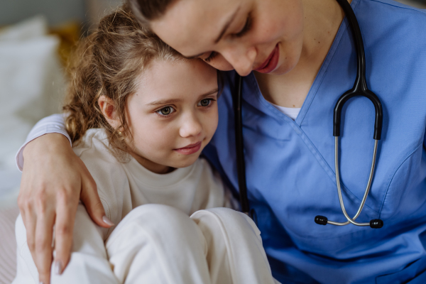 Young doctor consoling little girl in a hospital room.