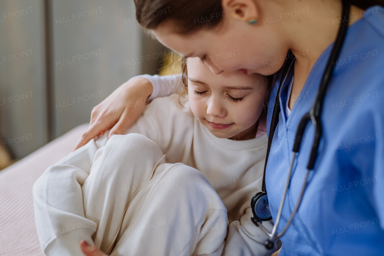 Young doctor consoling little girl in a hospital room.