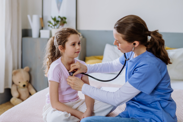 Young doctor taking care of little girl in a hospital room.