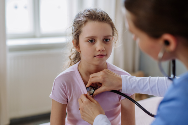 Young doctor taking care of little girl in a hospital room.