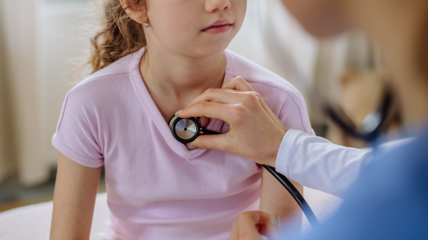 Young doctor taking care of little girl in a hospital room.