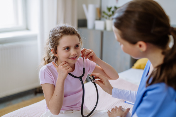 Young doctor taking care of little girl in a hospital room.