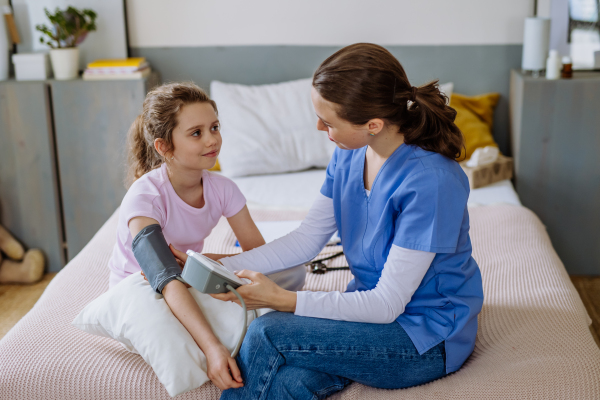 Young doctor taking care of little girl in a hospital room.