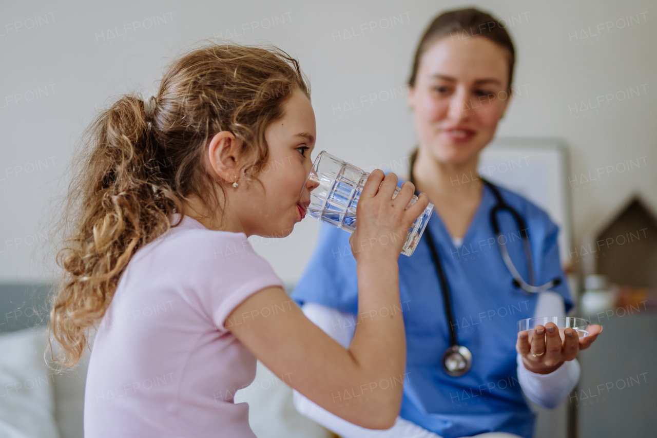 Young doctor taking care of little girl in a hospital room.