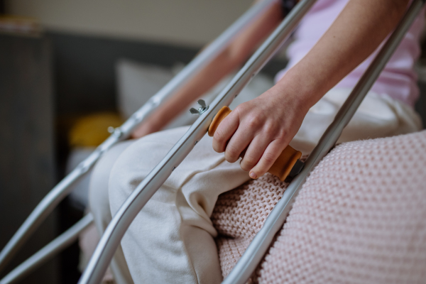 Mid section of little girl with broken leg sitting on bed.