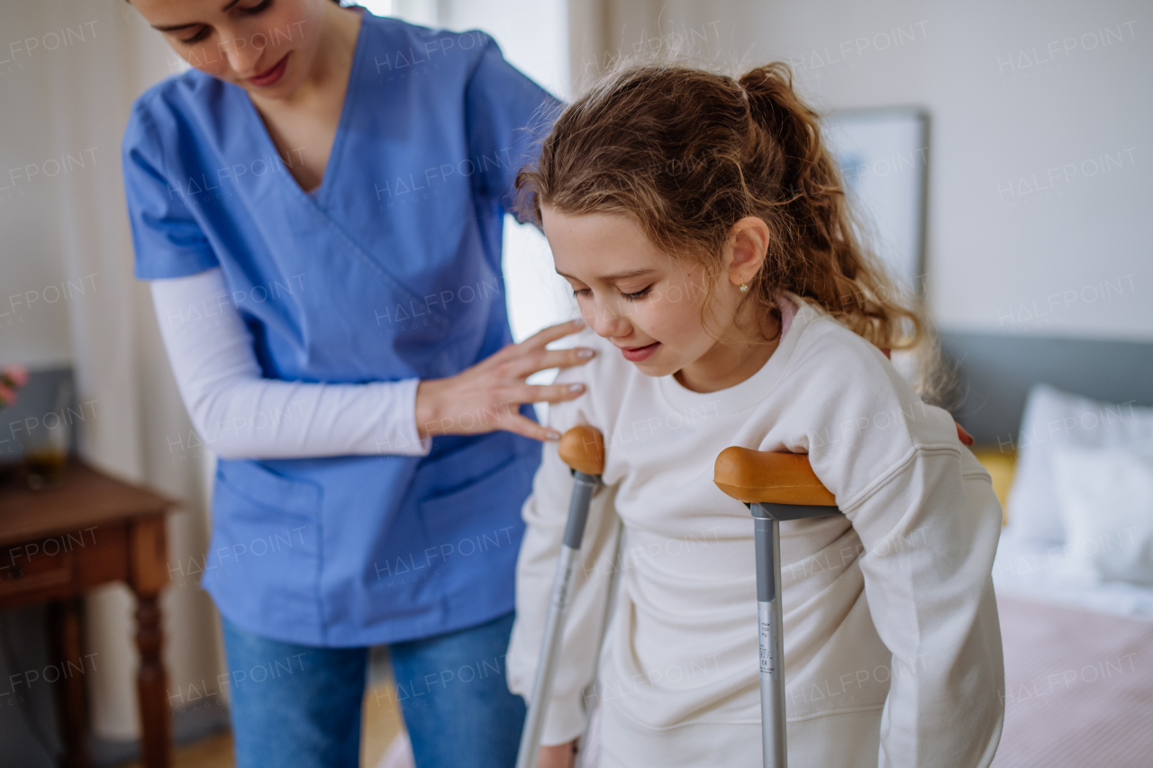 Young nurse helping to walk to little girl with a broken leg.