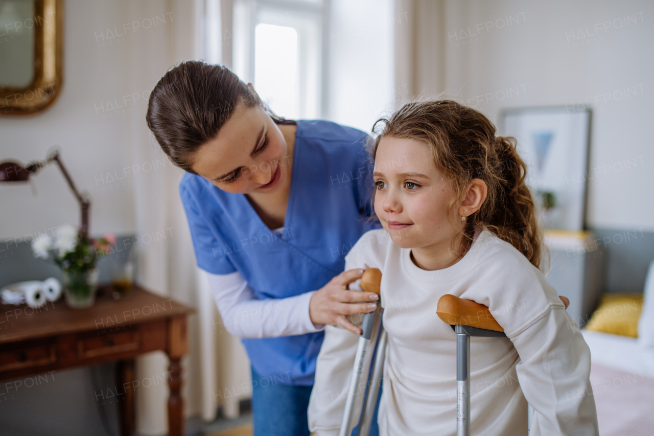 Young nurse helping to walk to little girl with a broken leg.