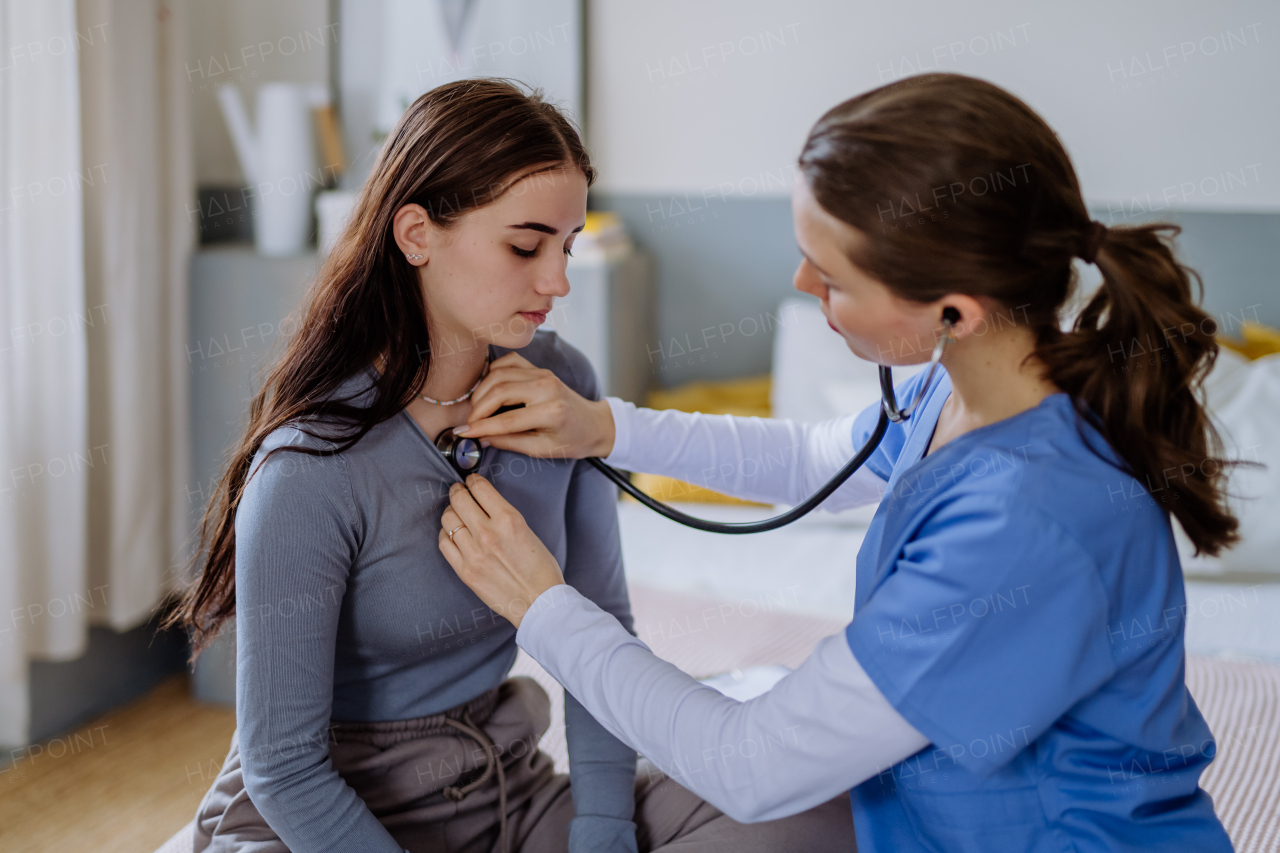 Young doctor examining a teenage girl in her office.