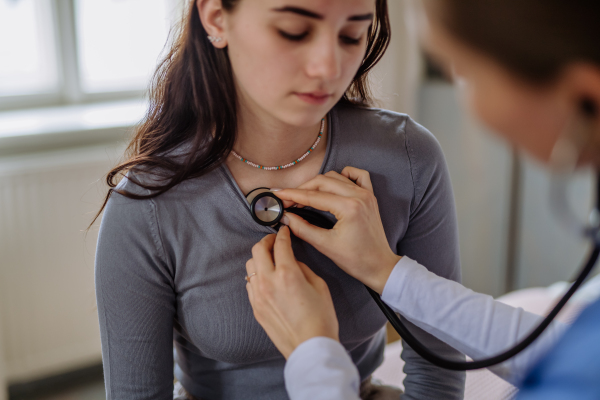 Young doctor examining a teenage girl in her office.