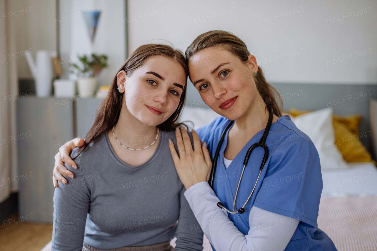 Young nurse taking care of a teenage girl, consoling her.