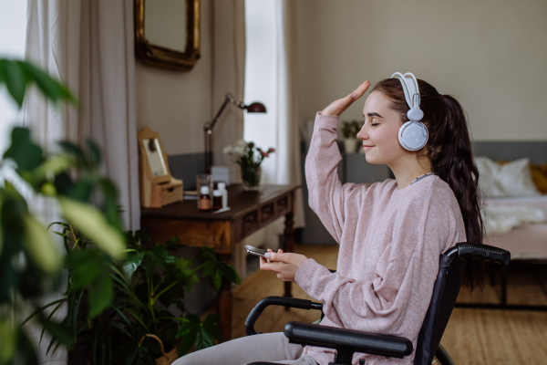 Young girl listening music trough headphones in a room.