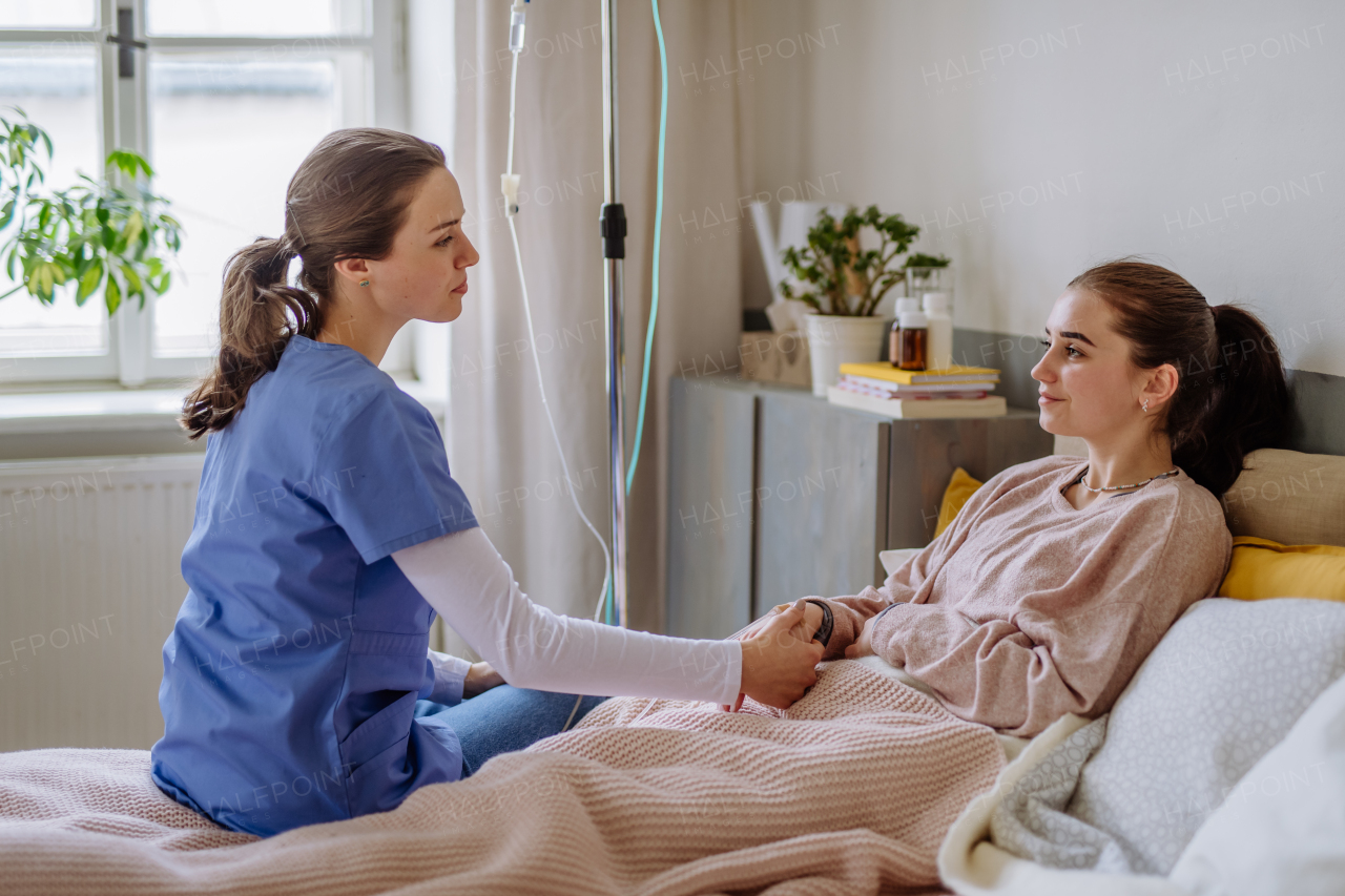 Young nurse taking care of teenage girl in a hospital room.