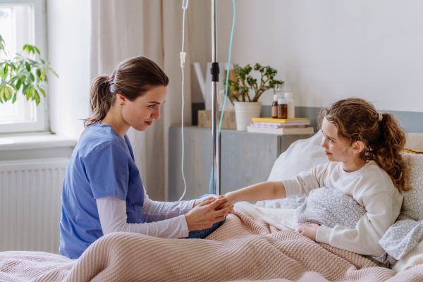 Young nurse taking care of teenage girl in a hospital room.