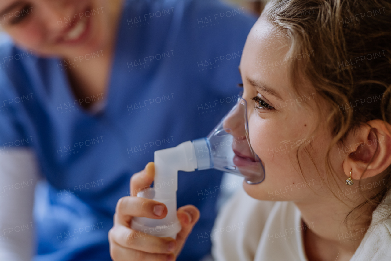 Little girl with inhaler in hospital room, a nurse chcecking her.