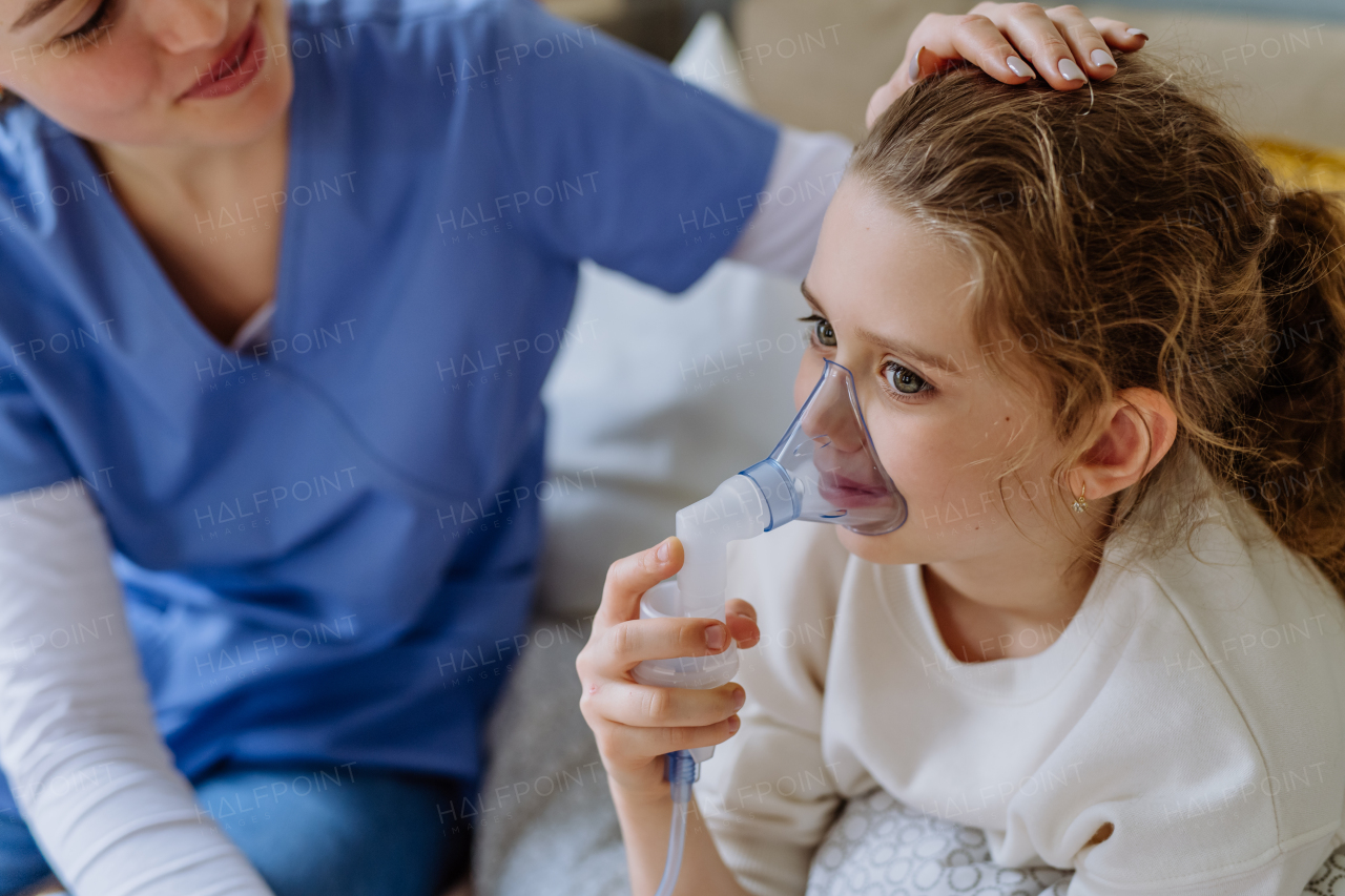 Little girl with inhaler in hospital room, a nurse chcecking her.