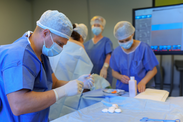 Healthcare team is preparing for surgery, opearation. Operating room with doctors, surgeons, anesthesiologist, scrub techs, surgical instrumentalist and nurses.