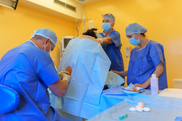 Spinal anesthesia before C-section. Anesthesiologist administering a dose of anesthetic near spinal cord, in the lower back.