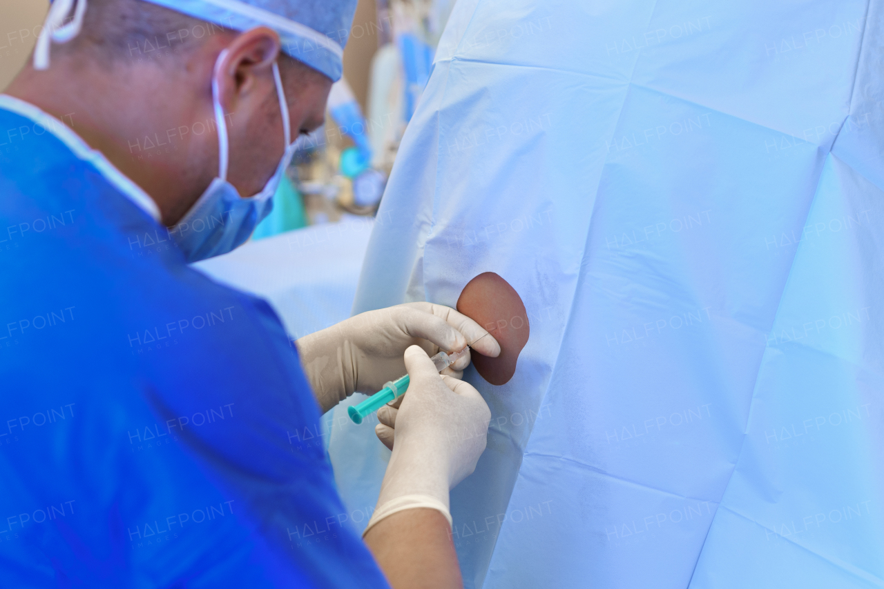 Spinal anesthesia before C-section. Anesthesiologist administering a dose of anesthetic near spinal cord, in the lower back.