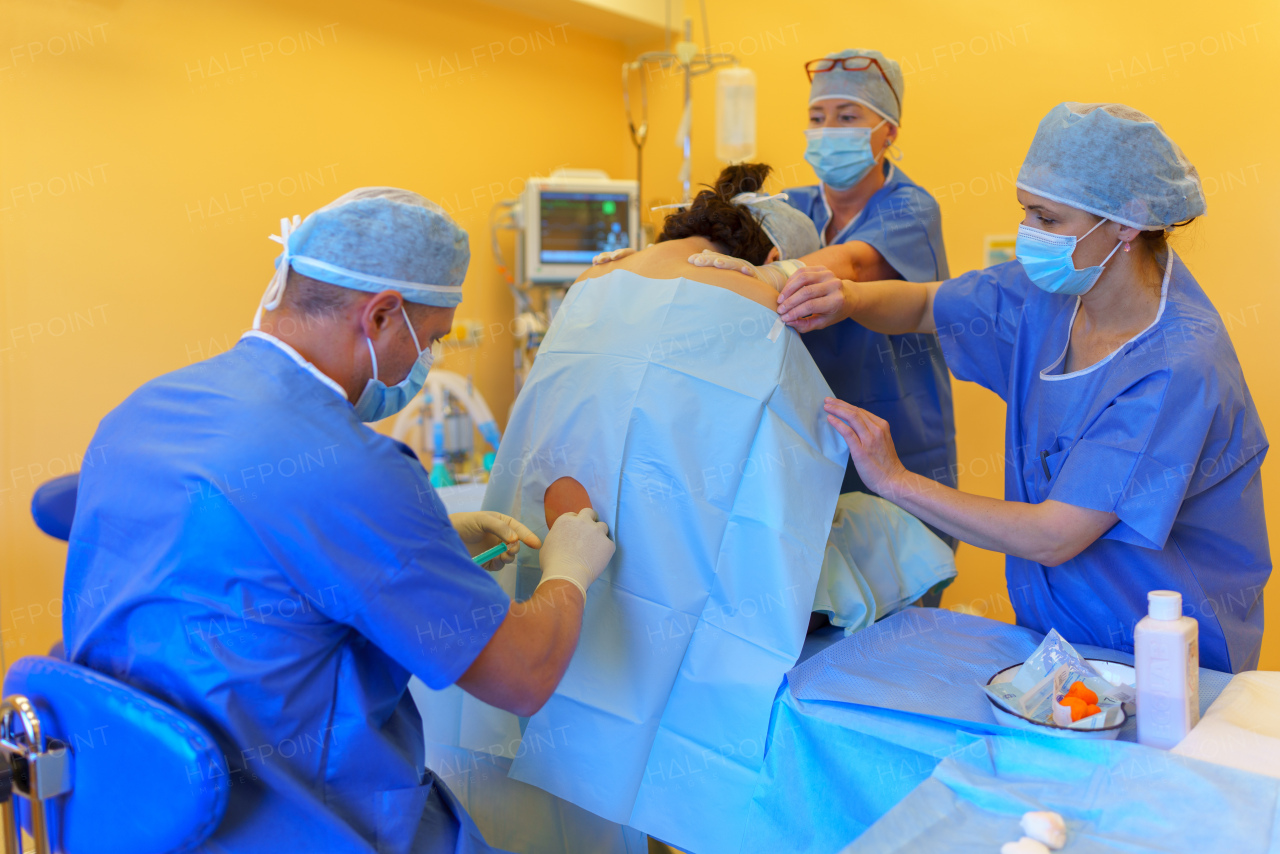 Spinal anesthesia before C-section. Anesthesiologist administering a dose of anesthetic near spinal cord, in the lower back.