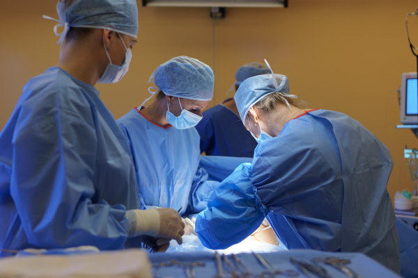 Gynecologist, obstetricians and nurses as medical team during cesarean section delivery. Team of doctors performing surgery, operation. Modern Maternity hospital.