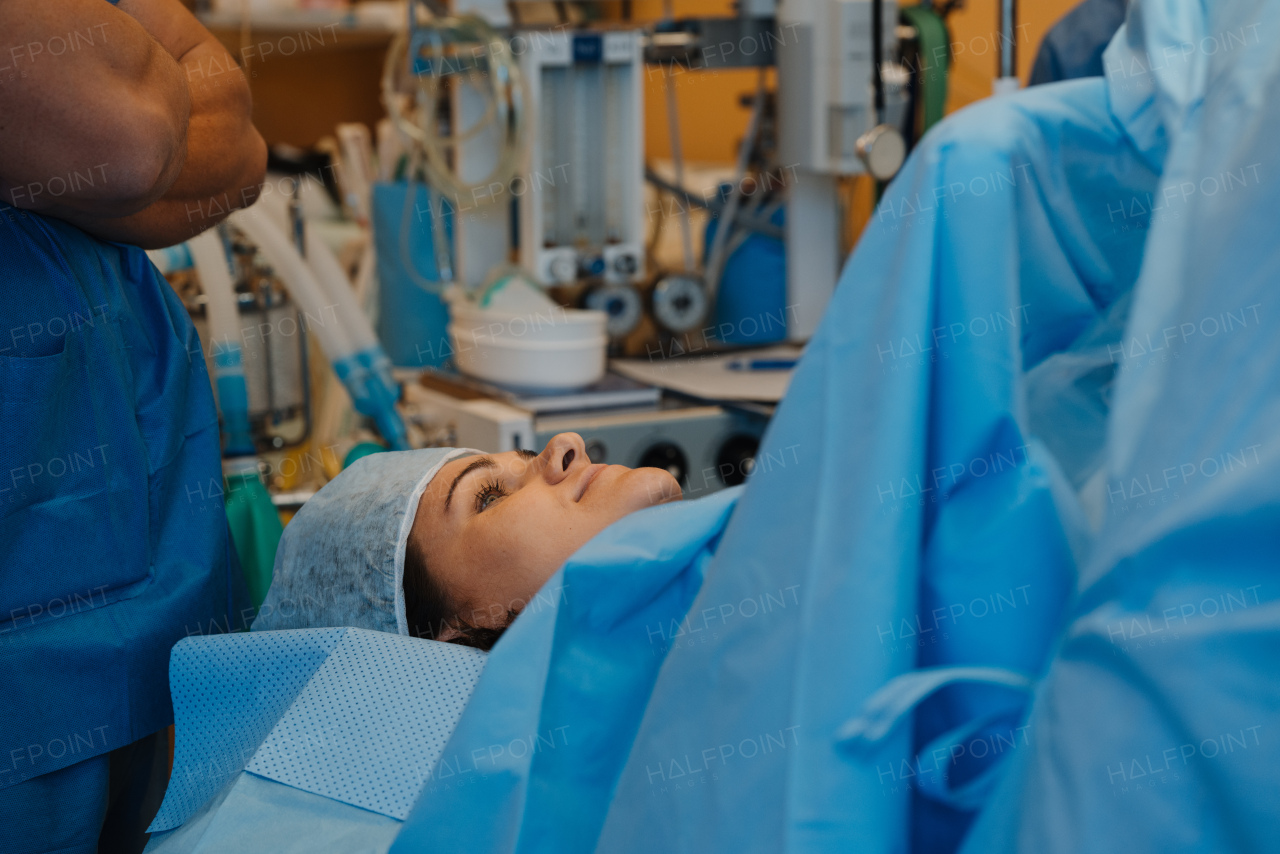 Mother during c-section delivery. Gynecologist, obstetricians and nurses as medical team during cesarean childbirth. Team of doctors performing surgery, operation. Modern Maternity hospital.