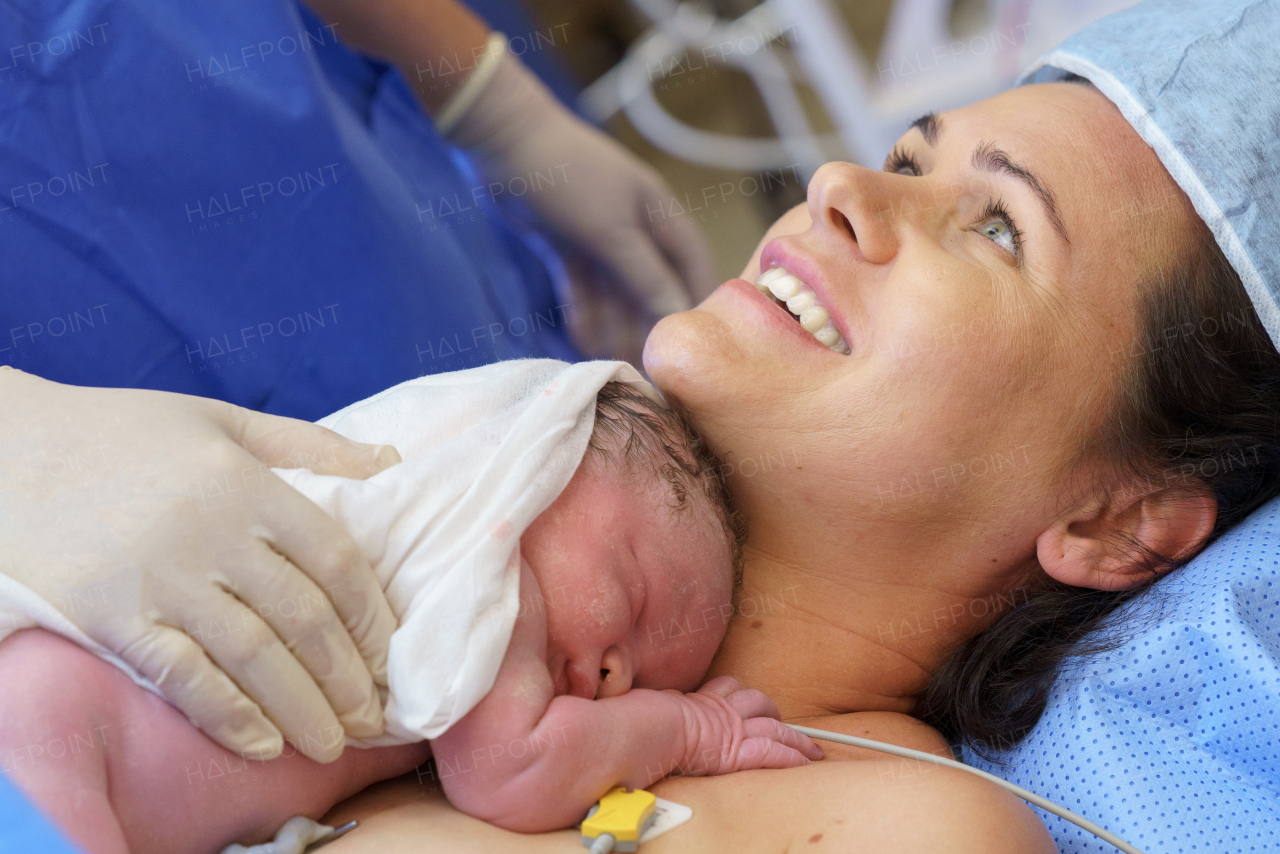 Happy mother bonding with newborn baby right after birth by c-section. Bonding on operating room. Skin to skin contact.