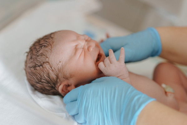 Neonatal nursers, doctor examining newborn baby, taking care of infant after birth. Neonatal care, newborn's health and well-being.