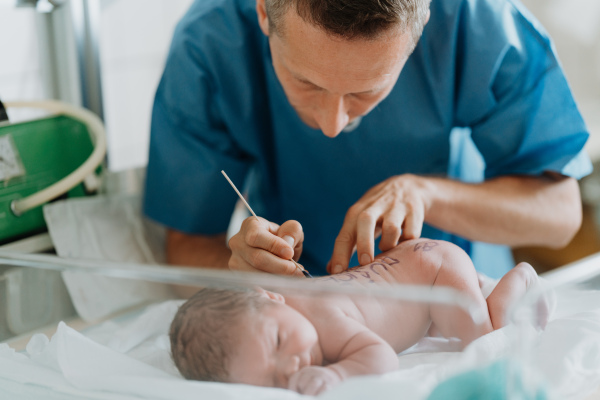 Neonatal nurse writing baby's name on skin. Healthcare team taking care of infant after birth. Neonatal care, newborn's health and well-being.