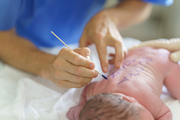 Neonatal nurse writing baby's name on skin. Healthcare team taking care of infant after birth. Neonatal care, newborn's health and well-being.