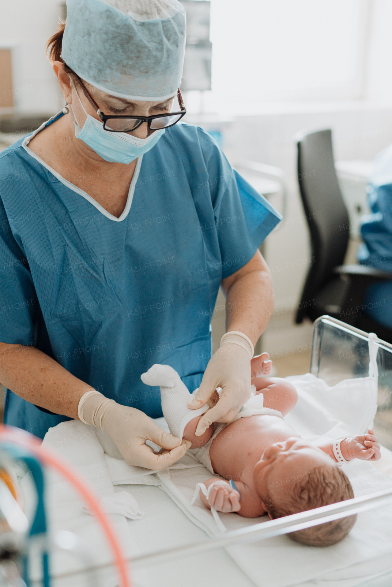 Neonatal nursers, doctor examining newborn baby, putting clothes on, taking care of infant after birth. Neonatal care, newborn's health and well-being.