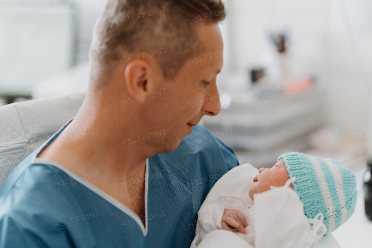 Male obstetrician or neonatologist doctor holding newborn baby. Doctor examining, taking care of infant after birth. Neonatal care, newborn's health and well-being.