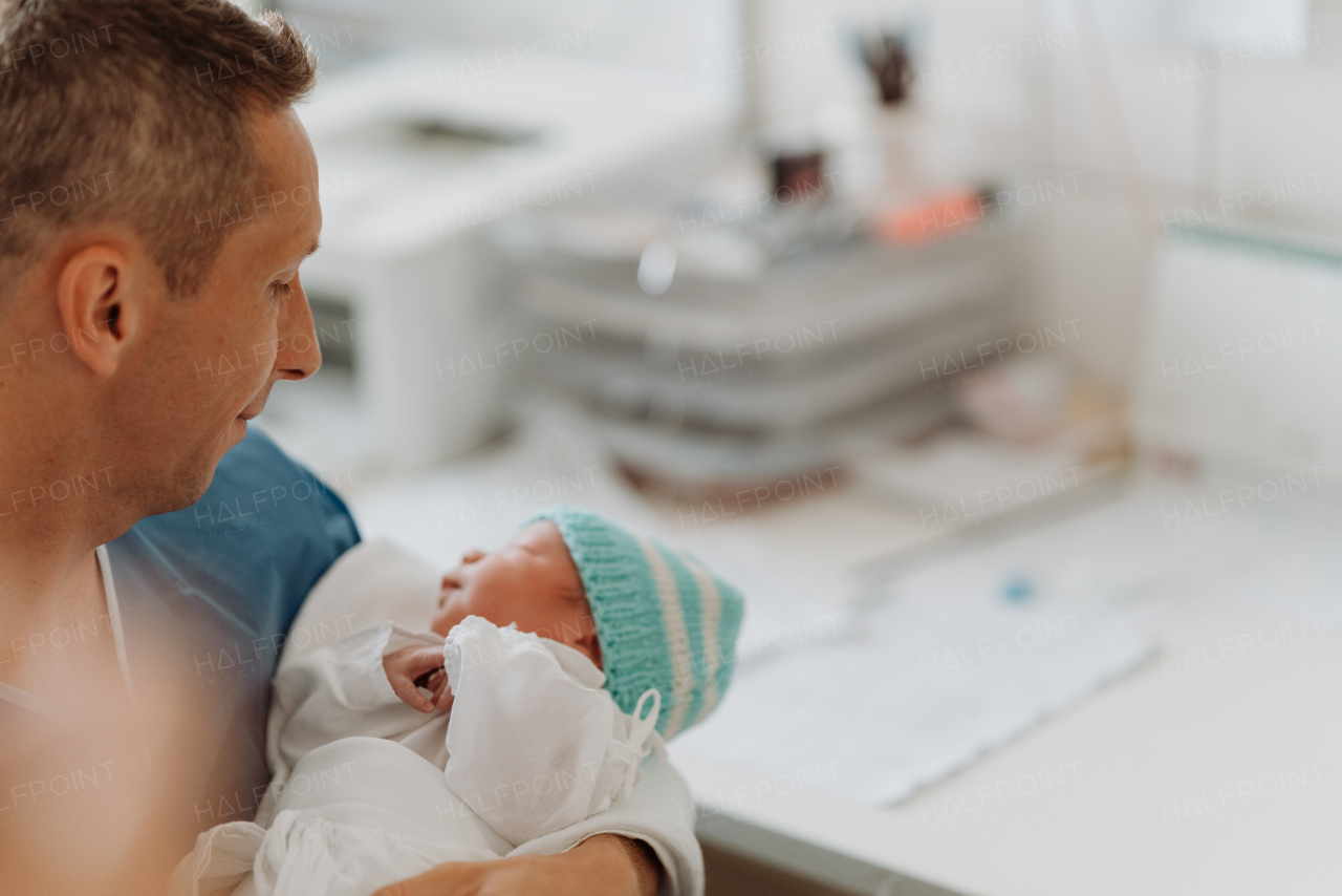 Proud father bonding with newborn baby right after birth. Holding baby for the first time. Skin to skin contact.