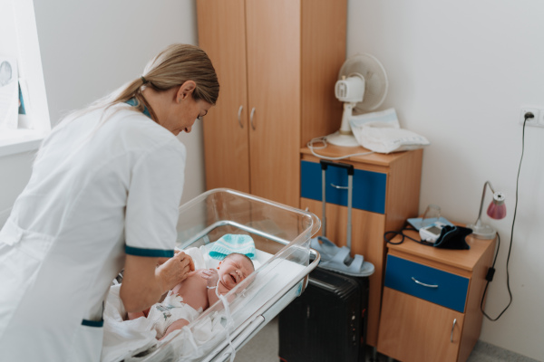 Neonatologist nurse taking care of newborn baby in mothers room. Neonatal care, newborn's health and well-being.