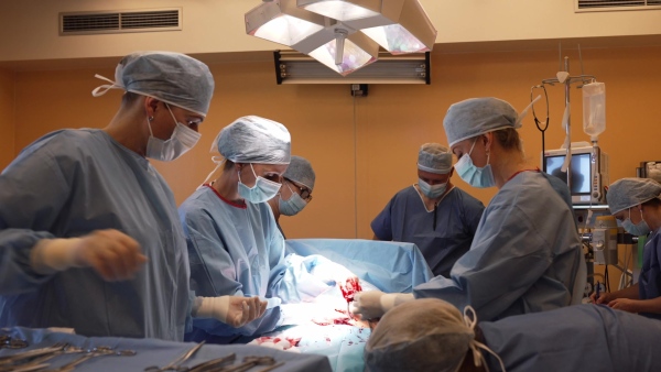 Delivery of of placenta after c-section childbrid. Gynecologist, obstetricians and nurses as medical team during cesarean section. Team of doctors performing surgery. Modern Maternity hospital.