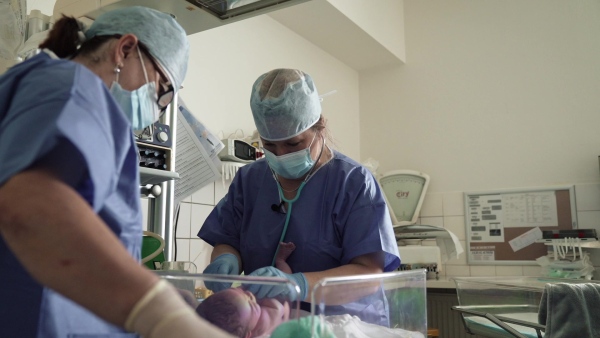 Neonatal nursers, doctor examining newborn baby, taking care of infant after birth. Cutting umbilical cord. Neonatal care, newborn's health and well-being.