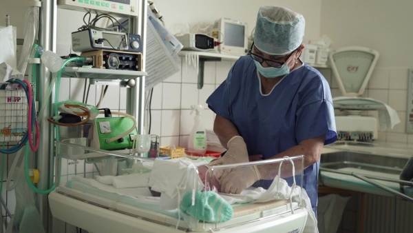 Neonatal nurser, doctor examining newborn baby, taking care of infant after birth. Cutting umbilical cord. Neonatal care, newborn's health and well-being.