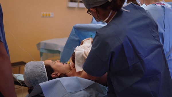 Happy mother bonding with newborn baby right after birth by c-section. Bonding on operating room. Skin to skin contact.