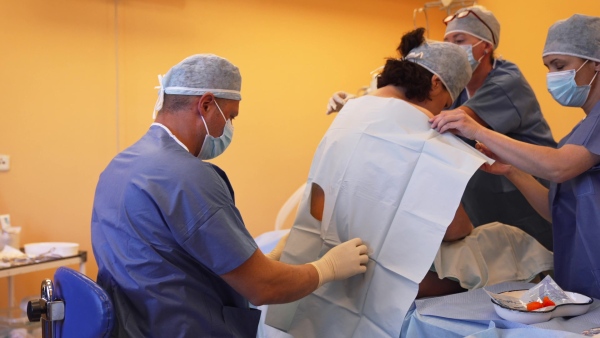 Spinal anesthesia before C-section. Anesthesiologist administering a dose of anesthetic near spinal cord, in the lower back.