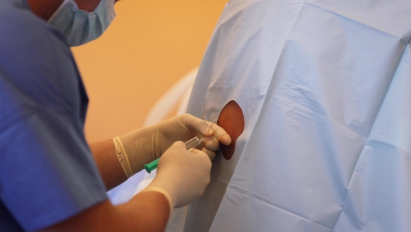 Spinal anesthesia before C-section. Anesthesiologist administering a dose of anesthetic near spinal cord, in the lower back.