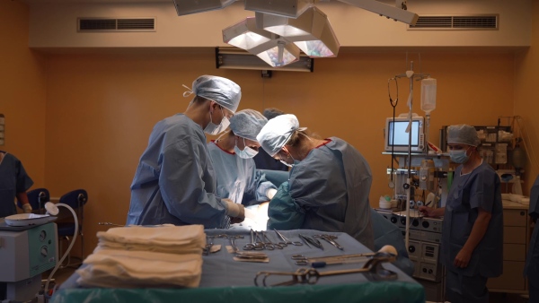 Delivery of of placenta after c-section childbrid. Gynecologist, obstetricians and nurses as medical team during cesarean section. Team of doctors performing surgery. Modern Maternity hospital.