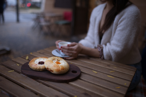 Close-up of woman with cup of coffee and fresh cakes, siting in cafe.