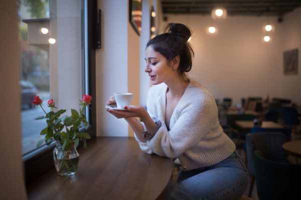 Young woman enjoying cup of coffee,sitting in cafe.