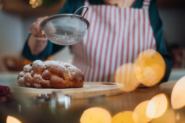 Close-up of senior woman sugaring Christmas bread.