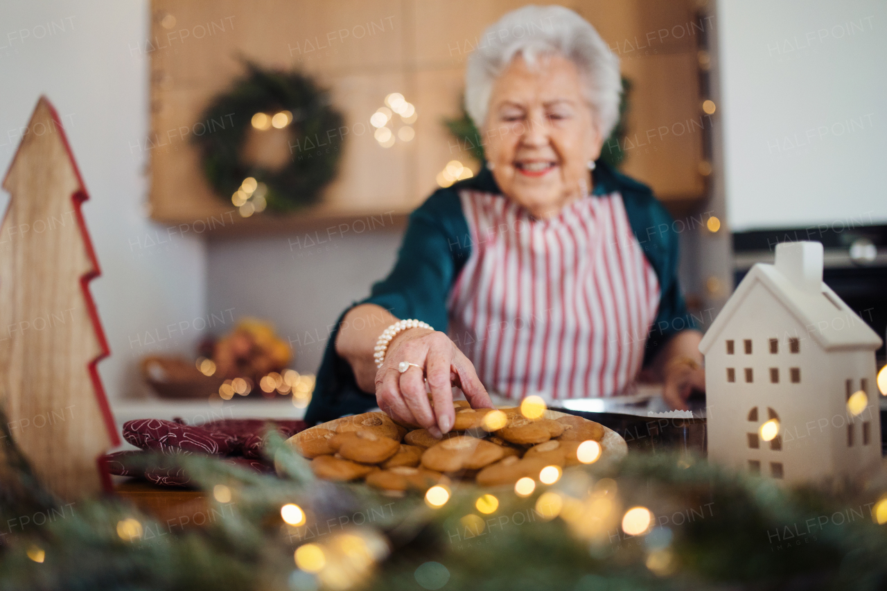 Happy senior woman baking a Christmas cakes at home.