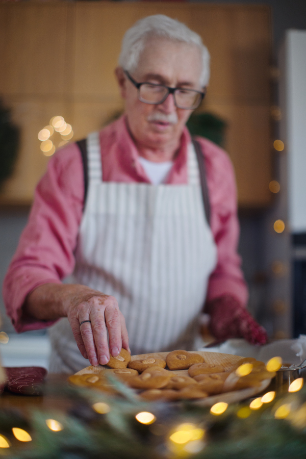 Senior man baking Christmas gingerbreads at home.