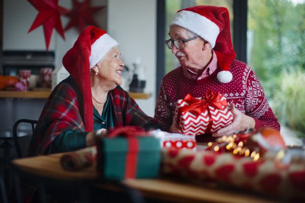 Senior couple celebrating Christmas, giving the gifts each other.